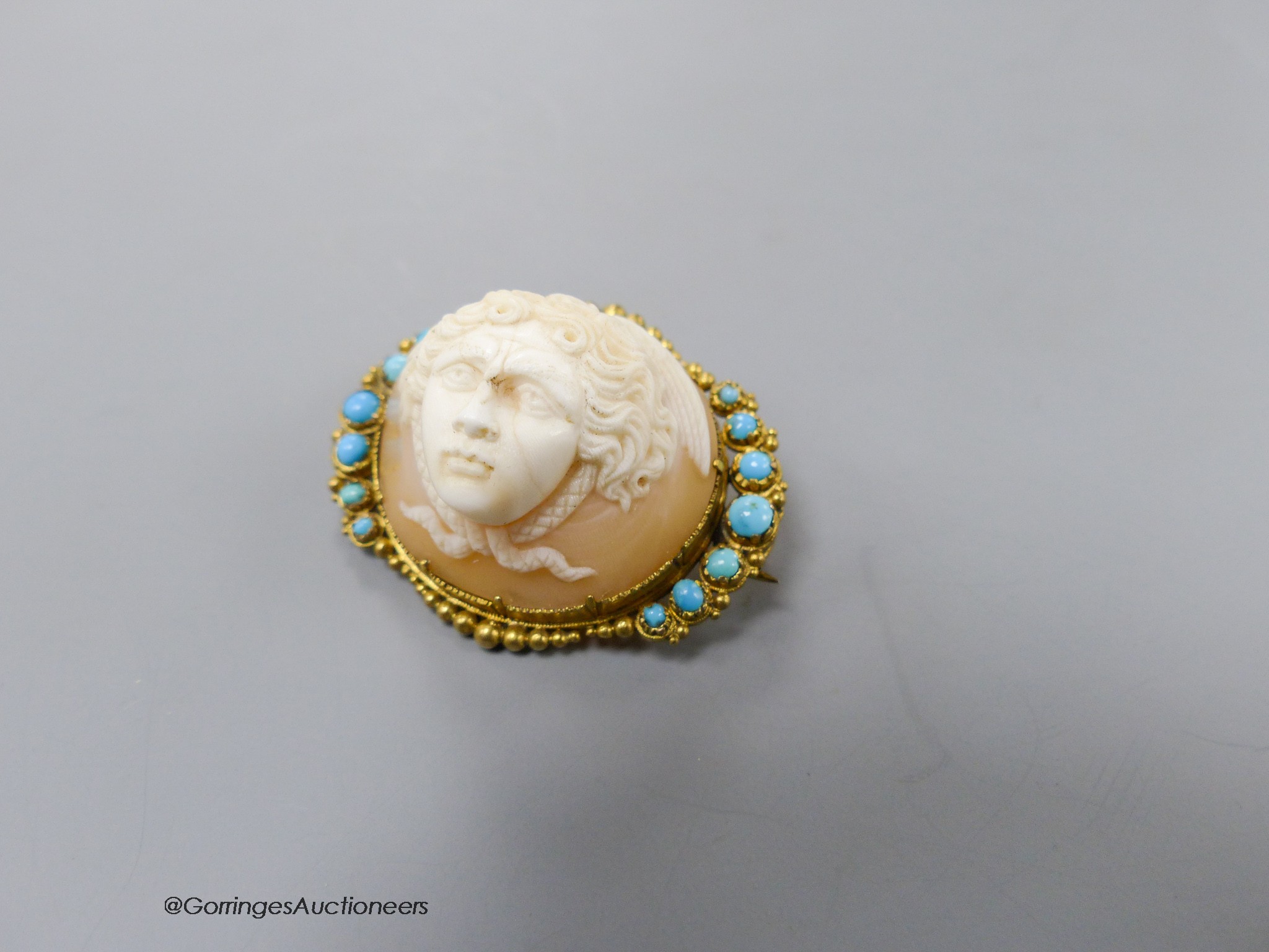 A Victorian yellow metal mounted cameo shell and turquoise set oval brooch, carved with the head of a cherub, 34mm, gross 9.2 grams.